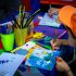 Kinder basteln am Tisch – Kinder gestalten bunte Karten und Bilder mit Stiften, Scheren und Bastelmaterialien.